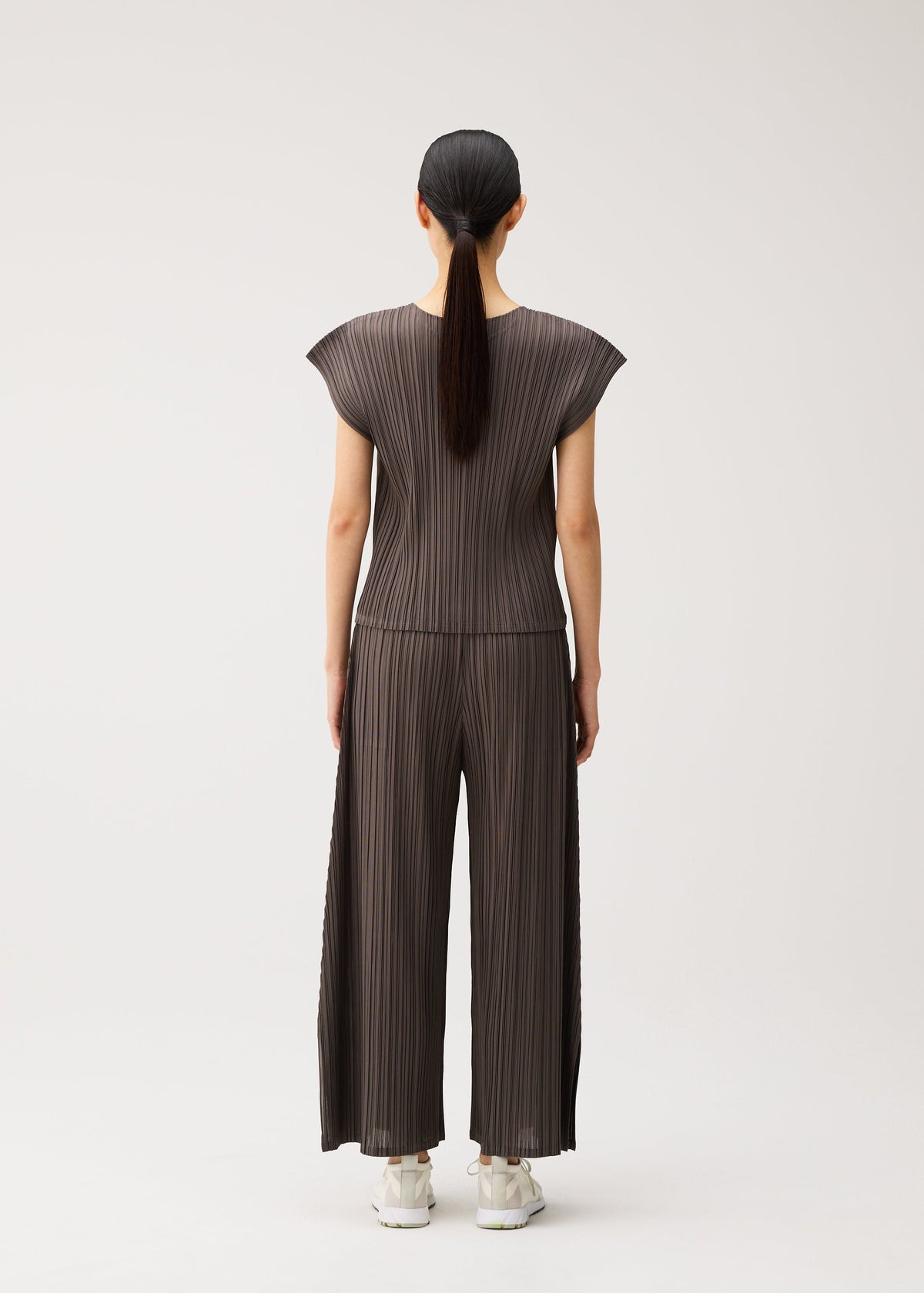 A model wears the PLEATS PLEASE ISSEY MIYAKE MELLOW PLEATS mellow-pleats-cap-sleeved-top-charcoal.