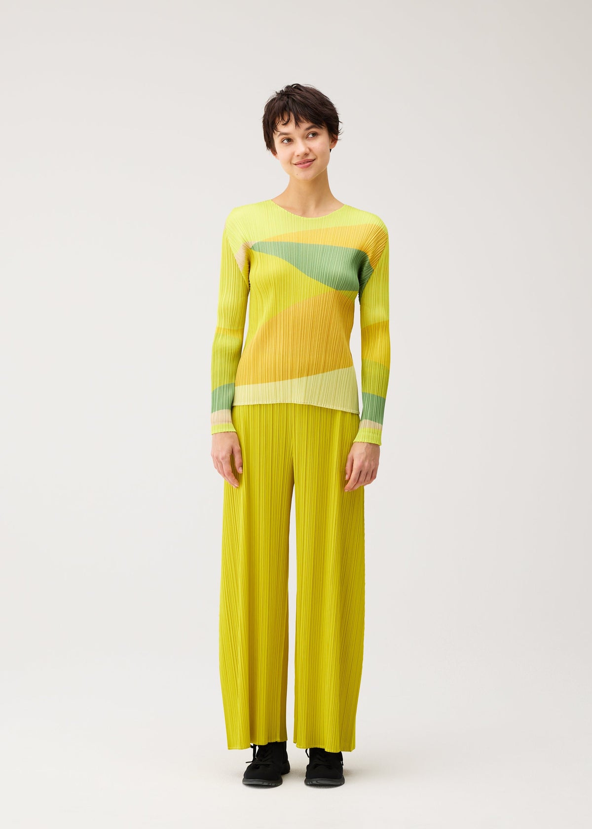 A model wears the PLEATS PLEASE ISSEY MIYAKE ORBIT orbit-top-green.