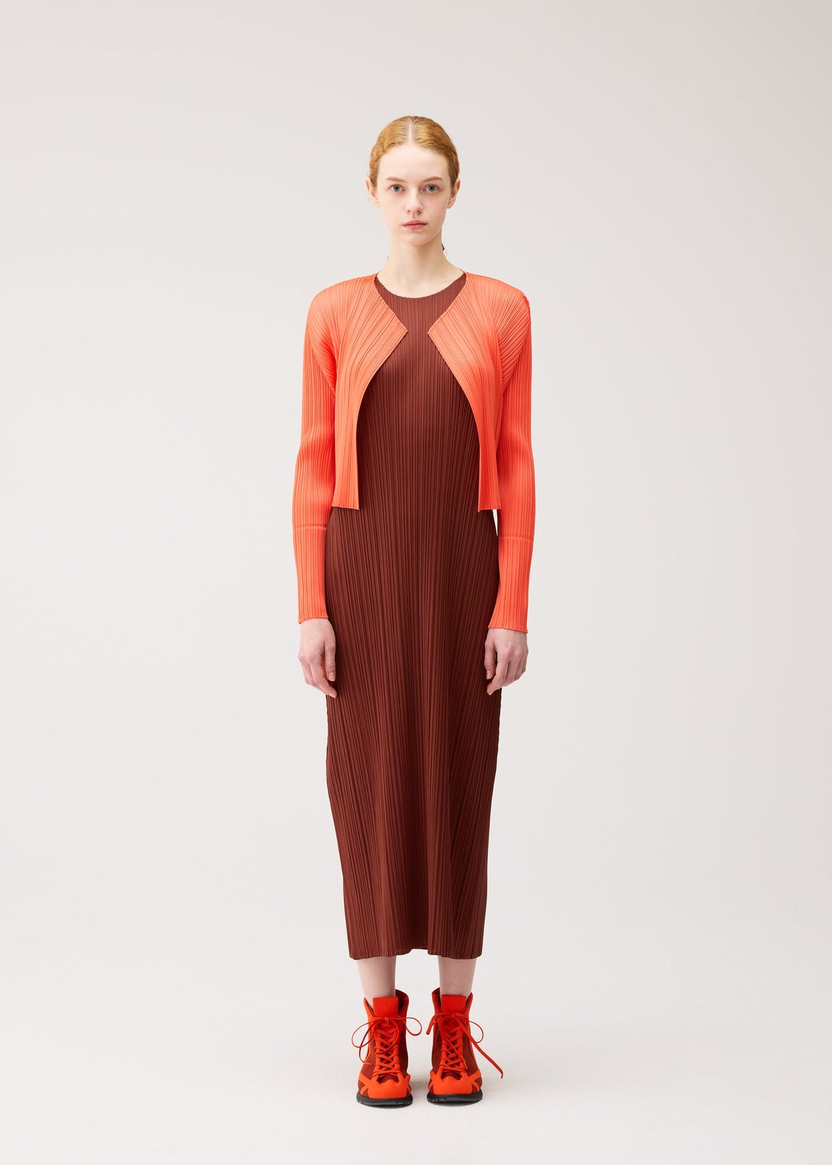 A model wears the PLEATS PLEASE ISSEY MIYAKE MONTHLY COLORS : SEPTEMBER monthly-colors-september-cardigan-red-brown.