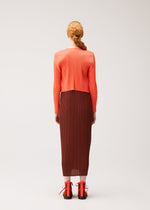 A model wears the PLEATS PLEASE ISSEY MIYAKE MONTHLY COLORS : SEPTEMBER monthly-colors-september-cardigan-red-brown.