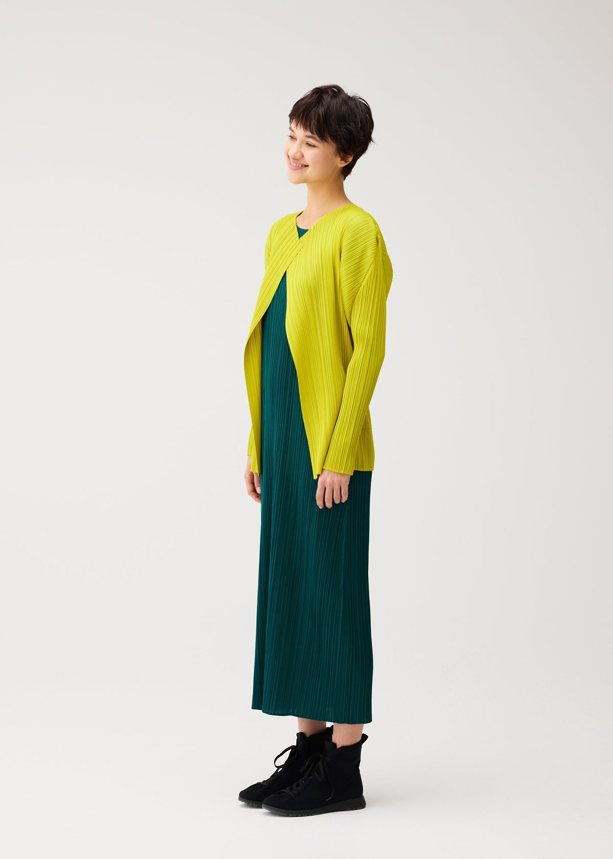 A model wears the PLEATS PLEASE ISSEY MIYAKE MONTHLY COLORS : OCTOBER monthly-colors-october-cardigan-yellow-ochre.