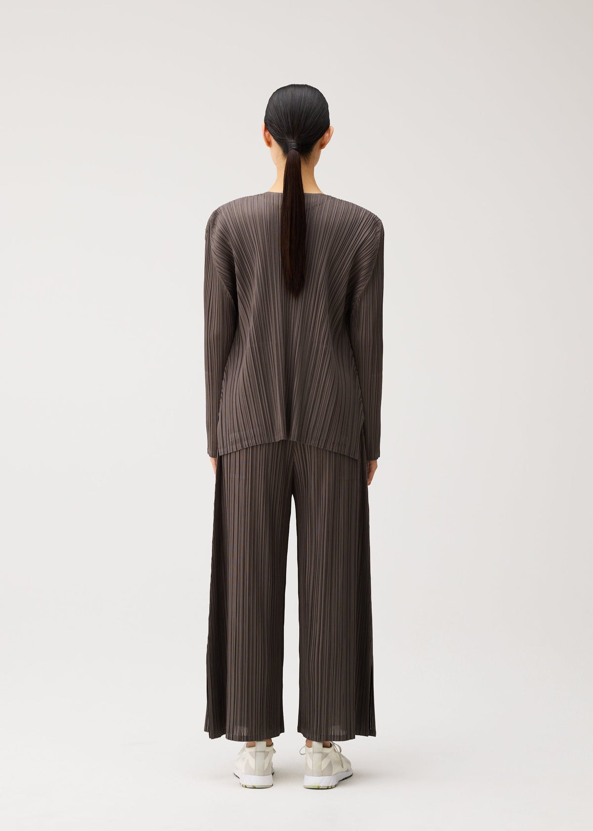 A model wears the PLEATS PLEASE ISSEY MIYAKE MELLOW PLEATS mellow-pleats-cardigan-charcoal.