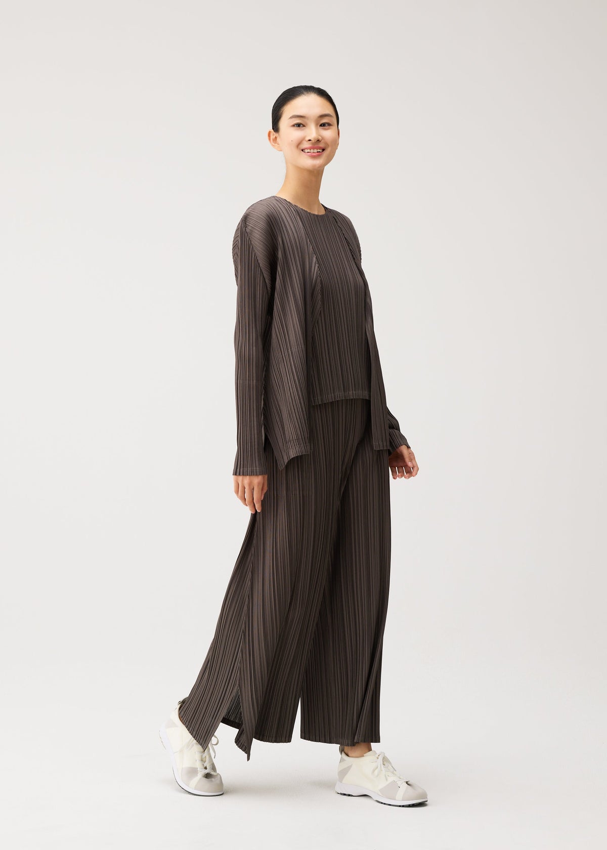 A model wears the PLEATS PLEASE ISSEY MIYAKE MELLOW PLEATS mellow-pleats-cardigan-black.