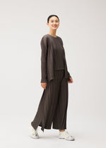 A model wears the PLEATS PLEASE ISSEY MIYAKE MELLOW PLEATS mellow-pleats-cardigan-charcoal.
