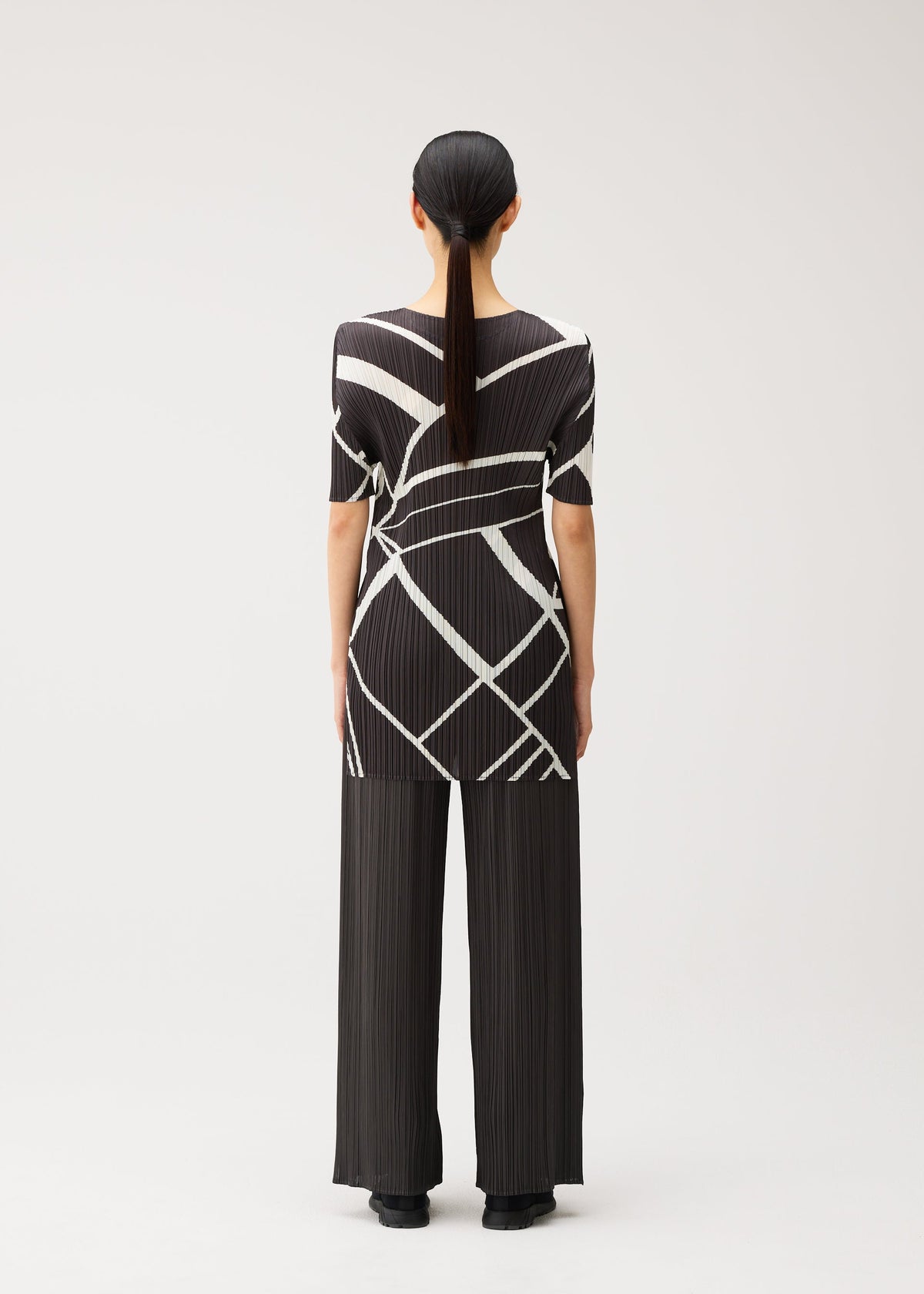 A model wears the PLEATS PLEASE ISSEY MIYAKE FOLD LINE fold-line-tunic-off-white.
