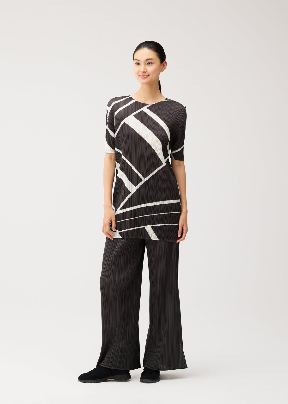 A model wears the PLEATS PLEASE ISSEY MIYAKE FOLD LINE fold-line-tunic-off-white.