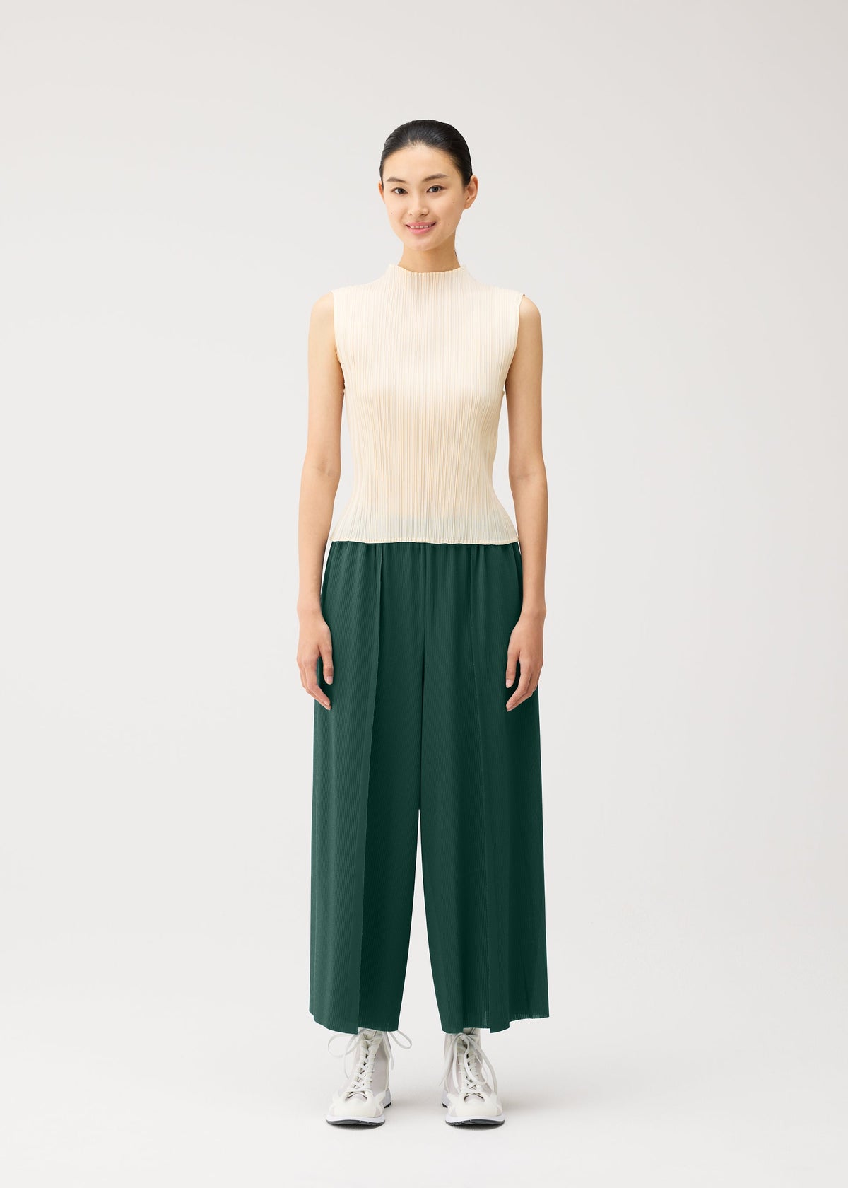 A model wears the PLEATS PLEASE ISSEY MIYAKE A-POC BOTTOMS a-poc-bottoms-trousers-flared-tapered-button-black.