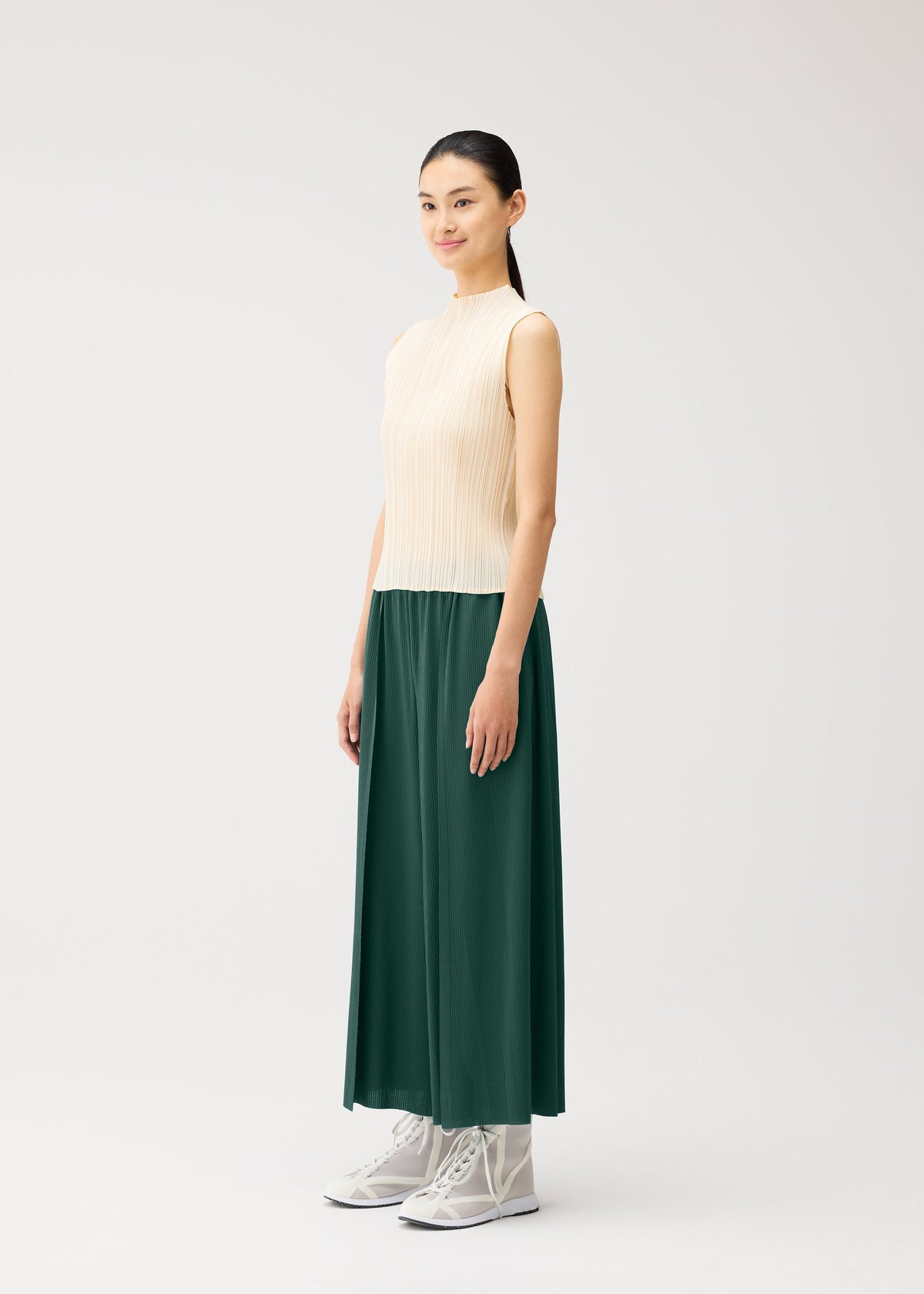 A model wears the PLEATS PLEASE ISSEY MIYAKE A-POC BOTTOMS a-poc-bottoms-trousers-flared-tapered-button-black.