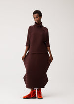 A model wears the PLEATS PLEASE ISSEY MIYAKE ZIG ZAG KNIT zig-zag-knit-top-red.