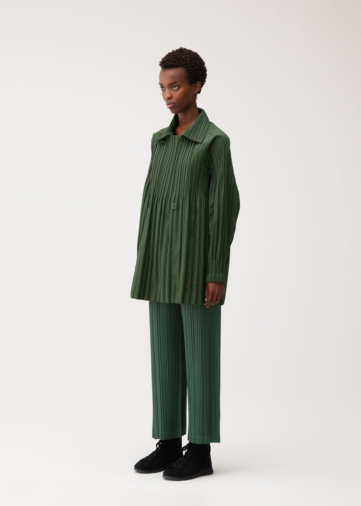 A model wears the PLEATS PLEASE ISSEY MIYAKE SMOOTH COAT smooth-coat-coat-khaki-1.