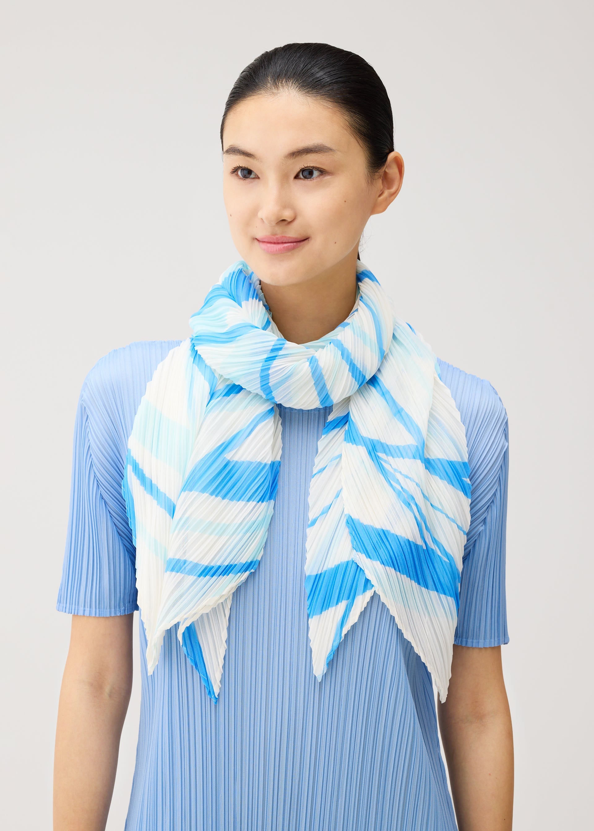A model wears the PLEATS PLEASE ISSEY MIYAKE FOLD LINE SCARF fold-line-scarf-stole-charcoal.