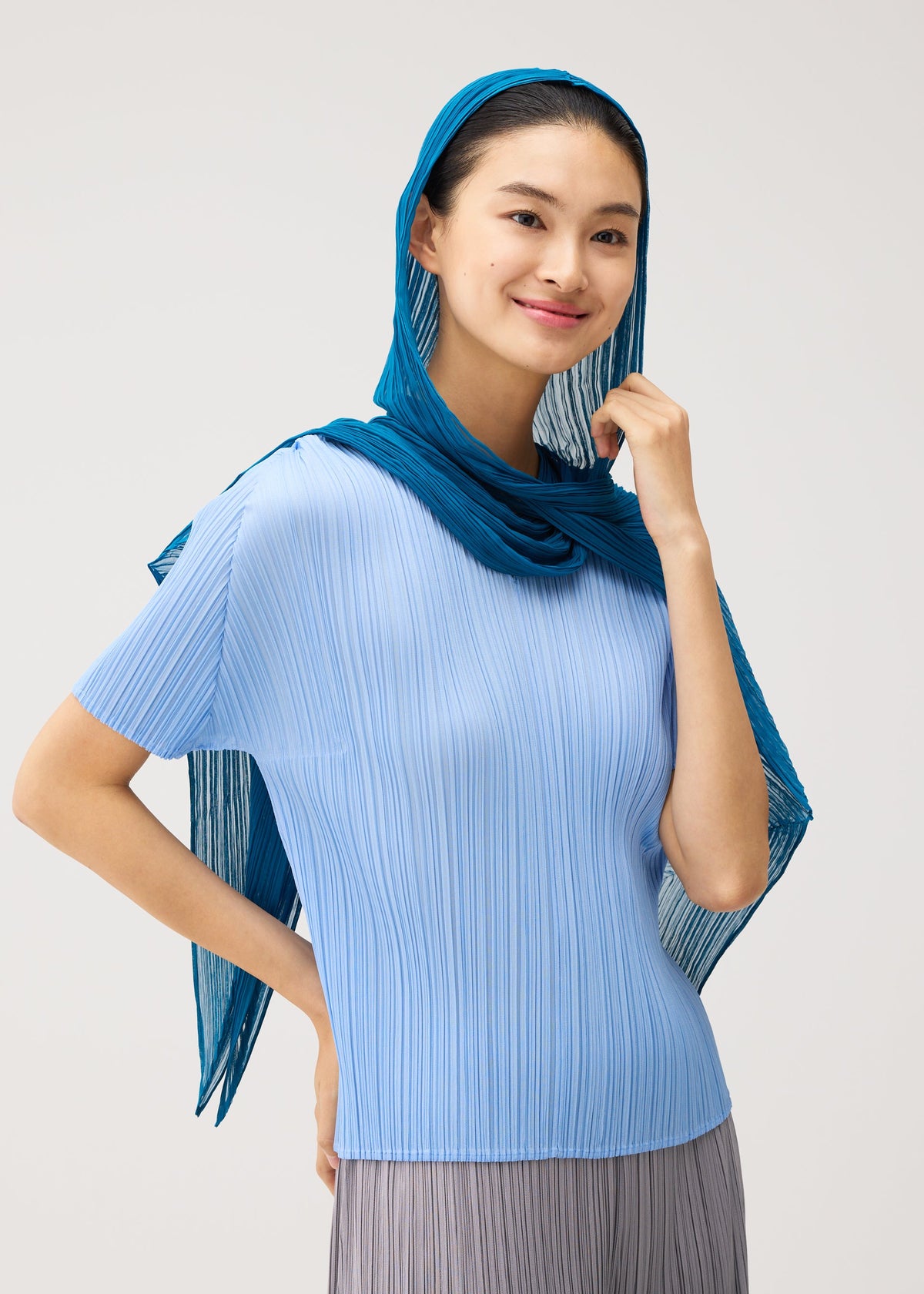 A model wears the PLEATS PLEASE ISSEY MIYAKE FOLD HOOD SCARF fold-hood-scarf-stole-navy.
