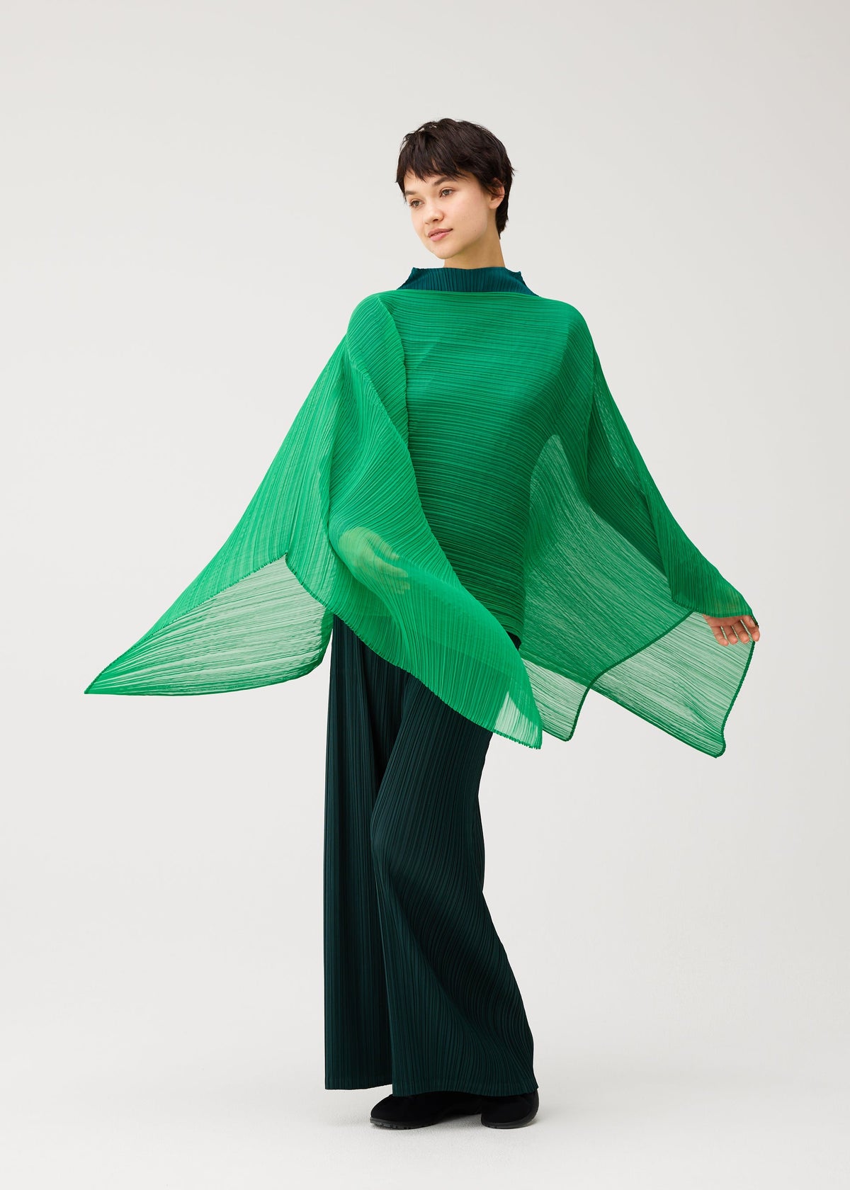 A model wears the PLEATS PLEASE ISSEY MIYAKE MADAME-T OCTOBER madame-t-october-stole-dark-green.