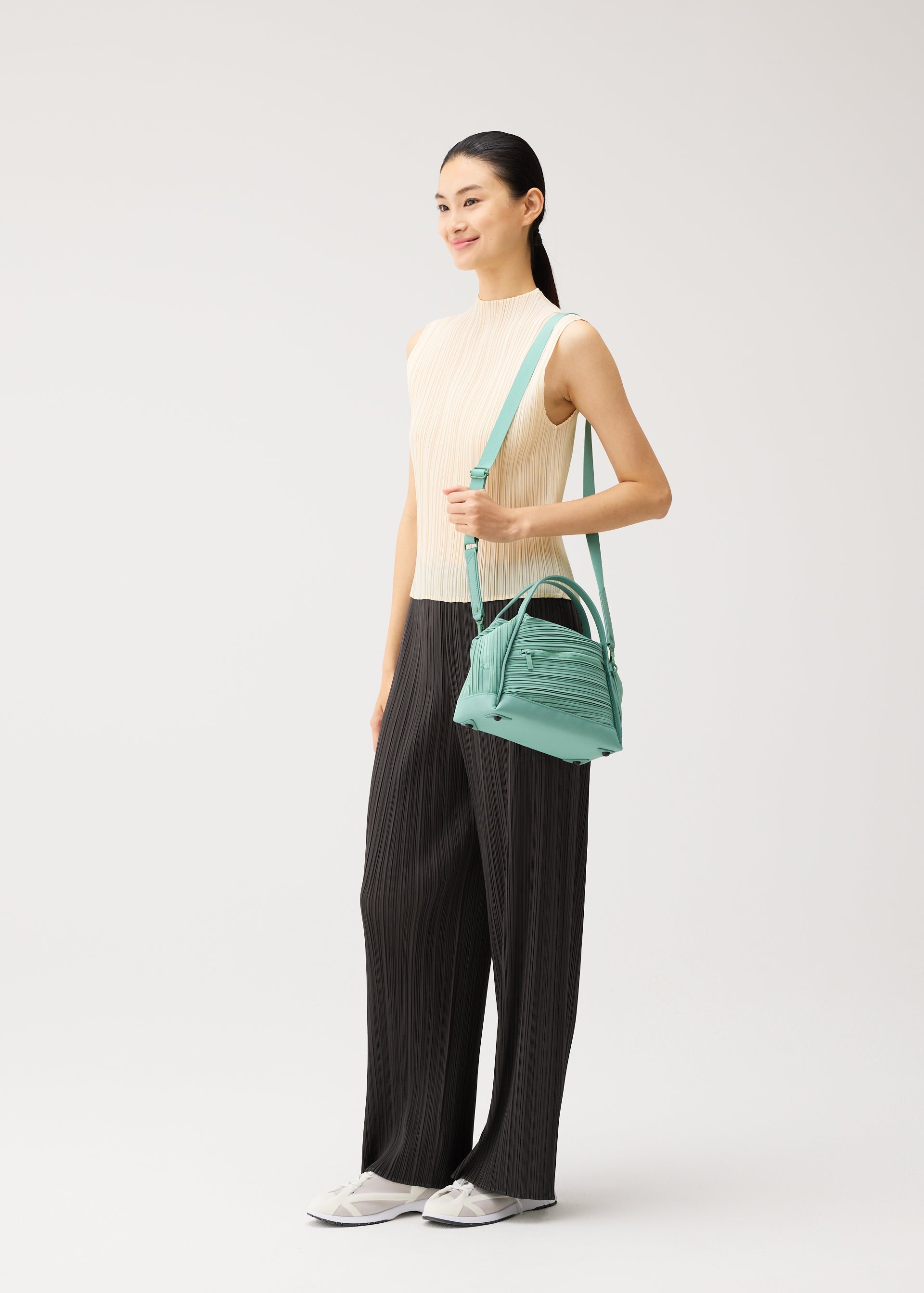 A model wears the PLEATS PLEASE ISSEY MIYAKE BIAS PLEATS BAG bias-pleats-bag-shoulder-bag-light-blue.